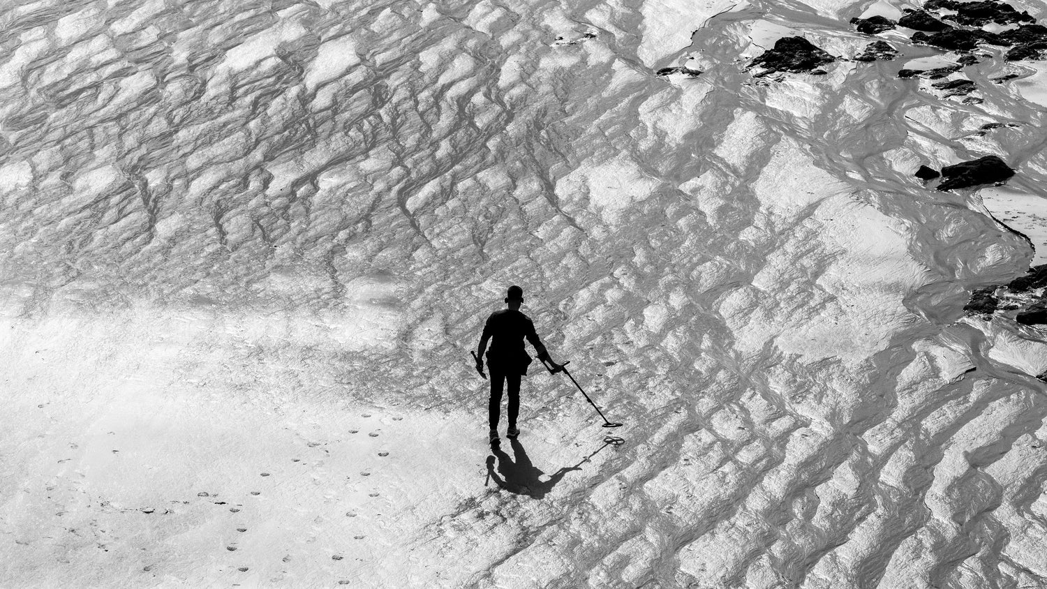 Metal detectorist searching a beach with equipment