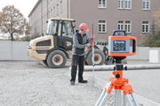 Nedo Heavy-Duty Elevating Tripod supporting a laser level, worker adjusting measuring rod on construction site.