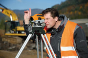Nedo Medium-Duty Aluminum Tripod Quick Clamp supporting surveying instrument used by man on construction site.