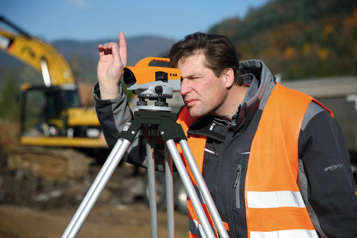 Nedo Medium-Duty Aluminum Tripod Quick Clamp supporting surveying instrument used by man on construction site.