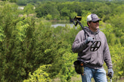 Detectorist carrying a Garrett ACE Apex metal detector across an open field