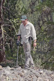 Prospector searching a rocky slope with the Garrett AT Gold