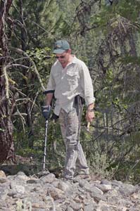 Prospector searching a rocky slope with the Garrett AT Gold