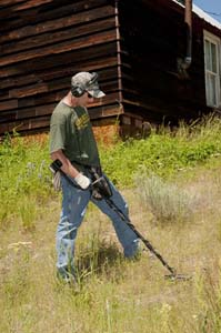 Detectorist relic hunting near an old cabin with the Garrett AT Gold
