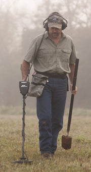 Detectorist walking a misty field with the Garrett AT Pro, finds pouch and digger