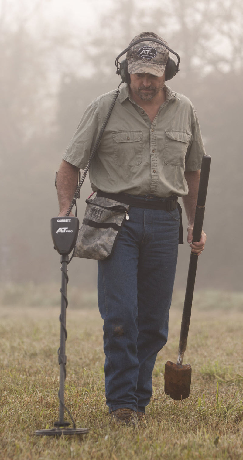 Detectorist walking a misty field with the Garrett AT Pro, finds pouch and digger