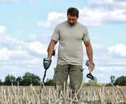 Detectorist hunting an open field with the Garrett AT Pro and a pinpointer
