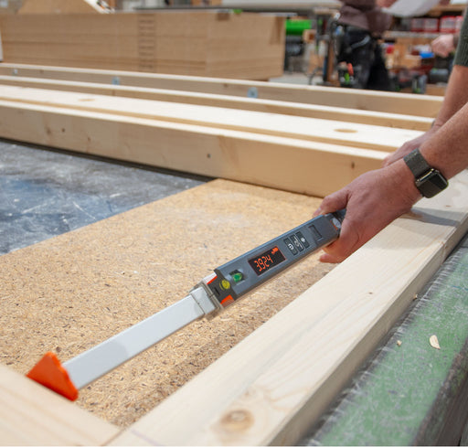 Nedo mEsstronic Digital Measuring Rod 28-118in — In-use: mEsstronic 2 digital rod (LED 39.24) with orange tip resting on OSB/timber framing, hand at the head.