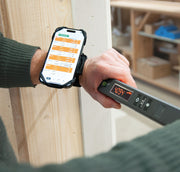 Nedo mEsstronic Digital Measuring Rod 28-118in — In-use: mEsstronic 2 digital rod (LED 40.94 ft) held against timber framing with a smartphone strapped to the forearm running the Nedo app.